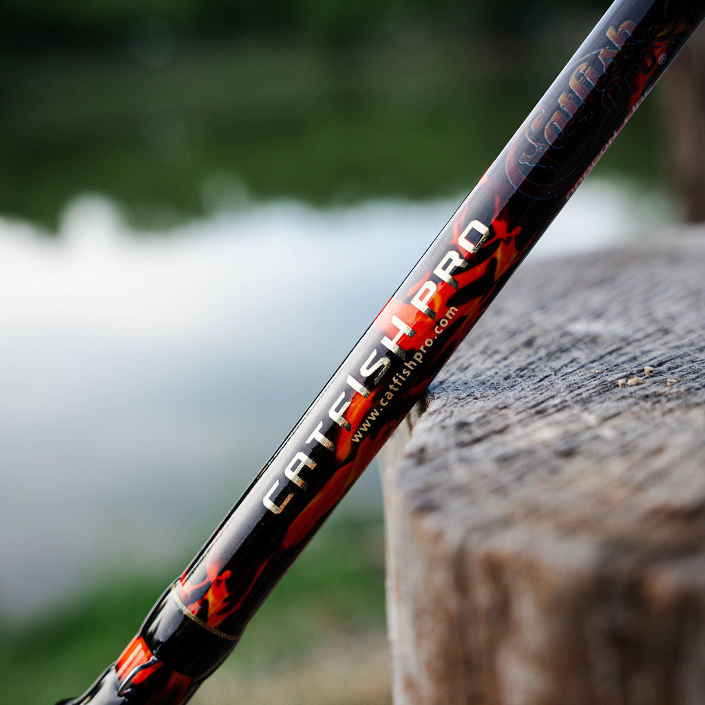 Fishing rod with red and black design on a wooden post by a blurred natural background
