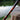 Fishing rod with red and black design on a wooden post by a blurred natural background