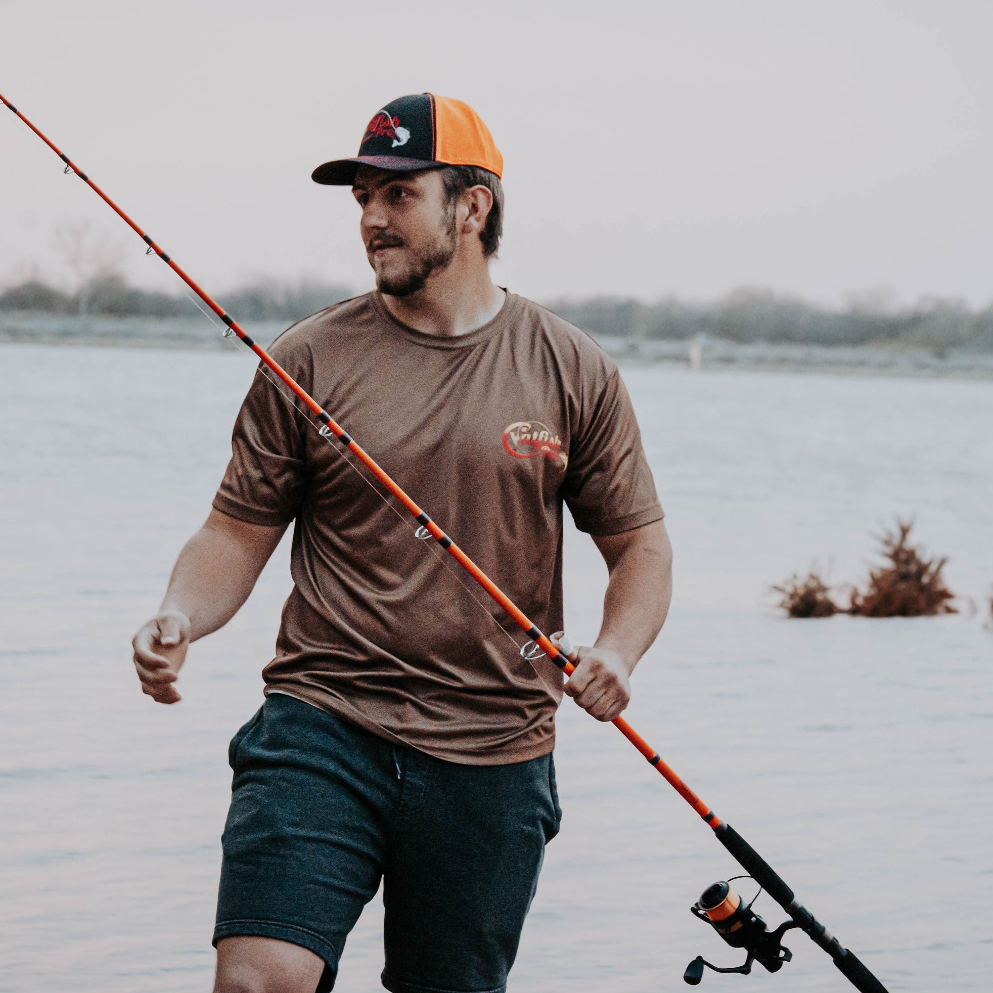 Man holding a fishing rod with the lake as a backdrop 