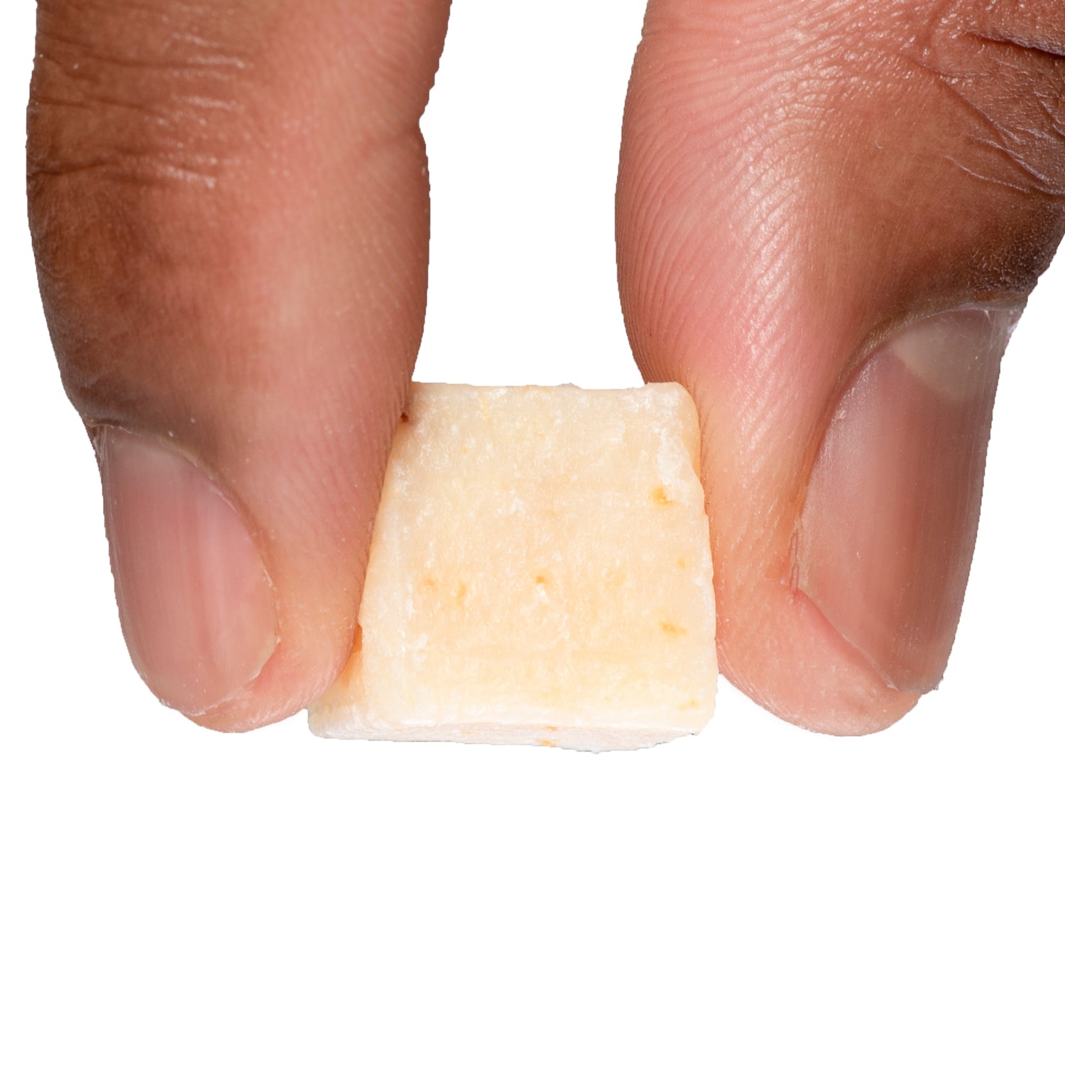 A close-up of a single Catfish Pro Garlic bait cube, held between two fingers, showing its texture and consistency.